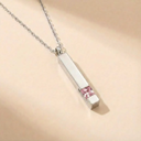 Necklace with a silver pendant featuring a pink gemstone on a beige background