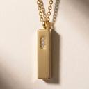 Gold pendant necklace with a small diamond on a beige background