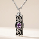 Silver and black cremation urn necklace with a purple gemstone on a beige background