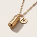 Gold necklace with a capsule pendant and paw charm on a light background