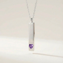 Necklace with a cylindrical pendant featuring a purple heart-shaped gem on a light background