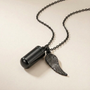 Black pendant necklace with a wing charm on a beige background