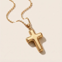 Gold cross necklace on a beige background