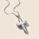 Silver cross necklace on a light beige background