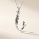 Silver fish hook pendant on a chain against a beige background