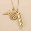 Gold necklace with wing charm, round pendant with engraved text, and cylindrical pendant on a beige background