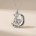 Silver cat-shaped pendant on a chain with engraved text against a beige background