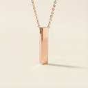 Rose gold necklace with a rectangular pendant on a beige background