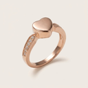 Rose gold ring with heart-shaped center and diamond accents on a light background