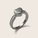 Silver heart-shaped ring with small diamonds on a light beige background