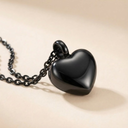 Black heart-shaped pendant on a chain against a beige background
