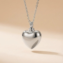 Silver heart-shaped pendant on a chain against a beige background