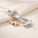 Silver pendant with a cylindrical gold component on a beige fabric background