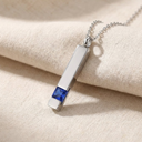Silver necklace with a blue gemstone pendant on a beige fabric background