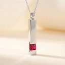 Silver pendant with a red gemstone on a soft beige background