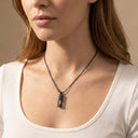 Woman wearing a necklace with a pendant against a neutral background