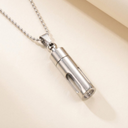 Silver cylindrical pendant necklace on a beige background