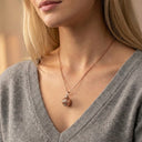 Necklace with a pendant worn by a person in a gray sweater.
