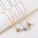 Three necklaces with spherical pendants in gold, silver, and rose gold on a light background.