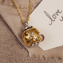 Gold and silver pendant necklace on a beige fabric background with 'love' card.