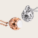 Two decorative pendants, one rose gold and one silver, on white background
