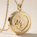 Gold necklace with a heart-shaped pendant featuring a paw print design on a light background.
