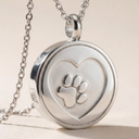 Silver locket with a heart design and paw print on a beige background