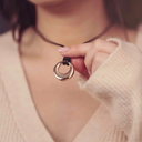 Close-up of a hand holding a gold necklace with a pendant against a blurred background.