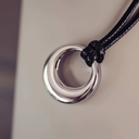 Close-up of a silver pendant on a black cord against a neutral background