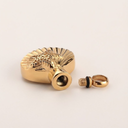 Gold-colored valve stem cap with a detailed design on a light beige background