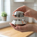Person holding two metallic bowls in a kitchen setting