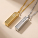 Two gold and silver necklaces with rectangular pendants on a beige background