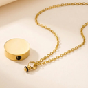 Gold necklace with a round pendant on a beige background