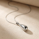 Silver necklace with a heart-shaped pendant on a beige fabric background