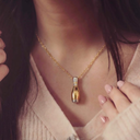 Close-up of a gold necklace with a unique pendant worn by a person.