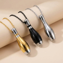 Three metallic keychains shaped like bowling pins on a beige surface.