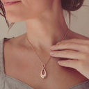 Rose gold necklace with a teardrop pendant worn by a person.