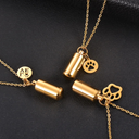 Gold necklaces with cylindrical pendants and paw print charms on a black background