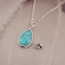 Turquoise pendant necklace on a neutral fabric background
