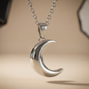Silver crescent moon necklace on a beige background
