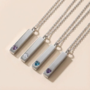 Set of four silver necklaces with gemstone pendants on a beige background