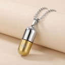 Gold and silver capsule-shaped pendant on a beige background