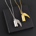 Two necklaces with winged urn pendants, one gold and one silver, on a black box.