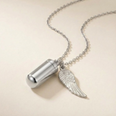 Silver necklace with a cylindrical pendant and angel wing charm on a beige background