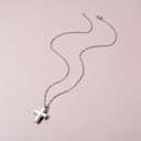 Silver cross necklace on a light pink background