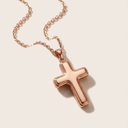 Rose gold cross necklace on a light beige background