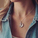 Close-up of a necklace with a cat pendant on a person wearing a denim jacket.