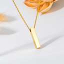 Gold necklace with a vertical bar pendant on a light background