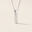 Silver necklace with a rectangular pendant on a light beige background