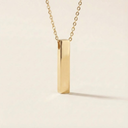 Gold necklace with a vertical bar pendant on a beige background